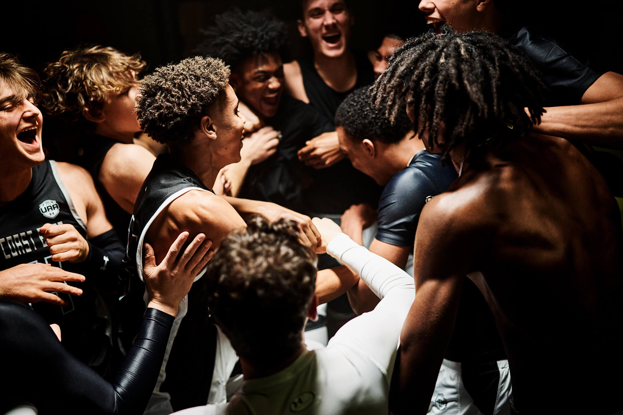 Group of young athletes celebrating together in a huddle, showing excitement and camaraderie.