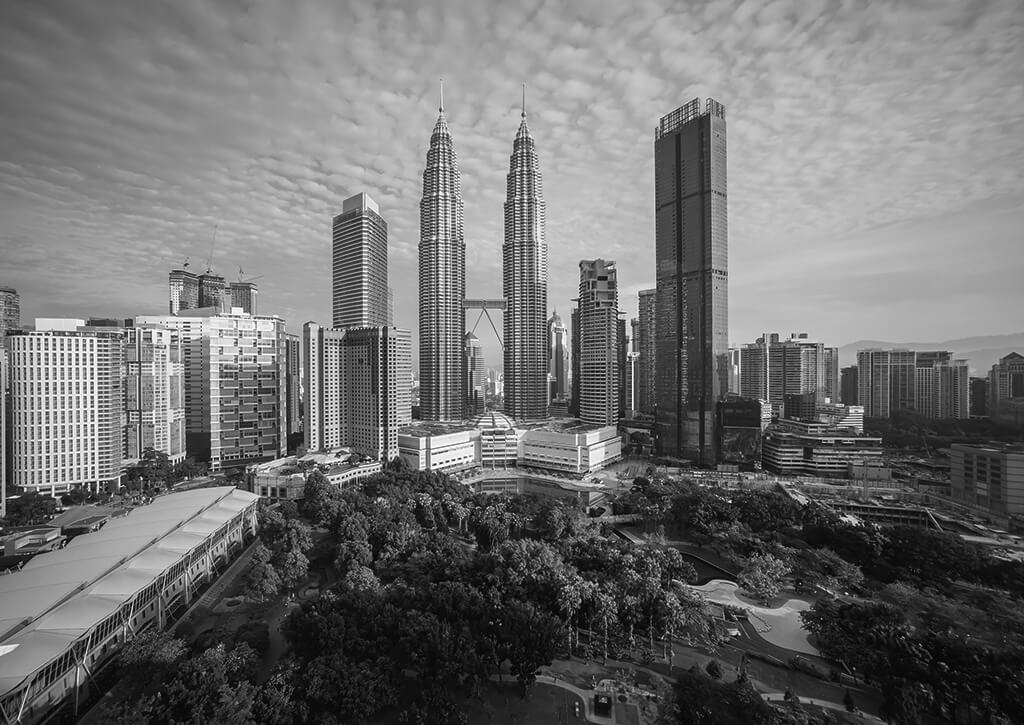 Black and white cityscape of Kuala Lumpur featuring the Petronas Twin Towers.